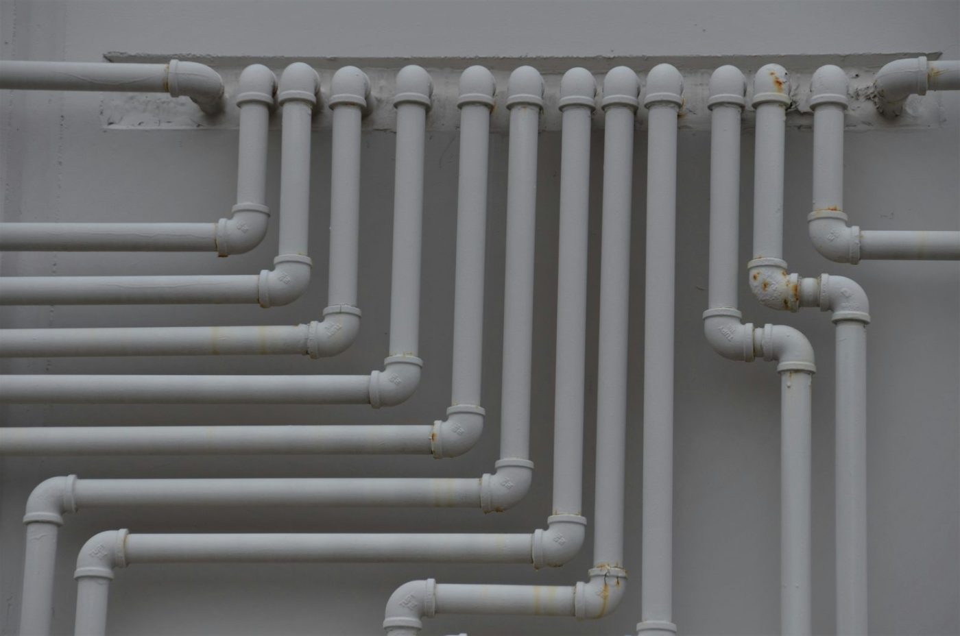 Neat runs of white pipework on a wall