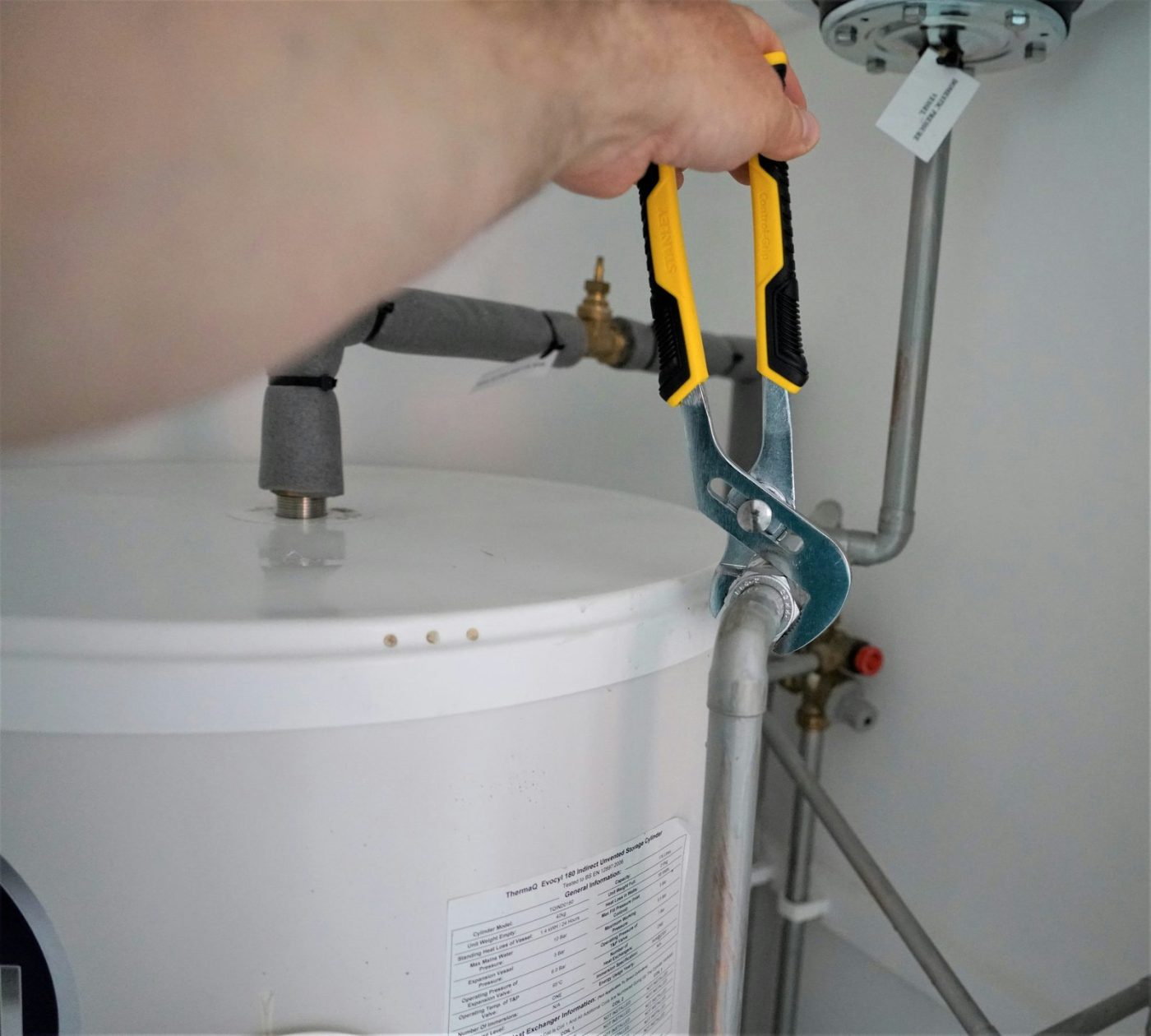 Plumber tightening a fitting on a hot water tank